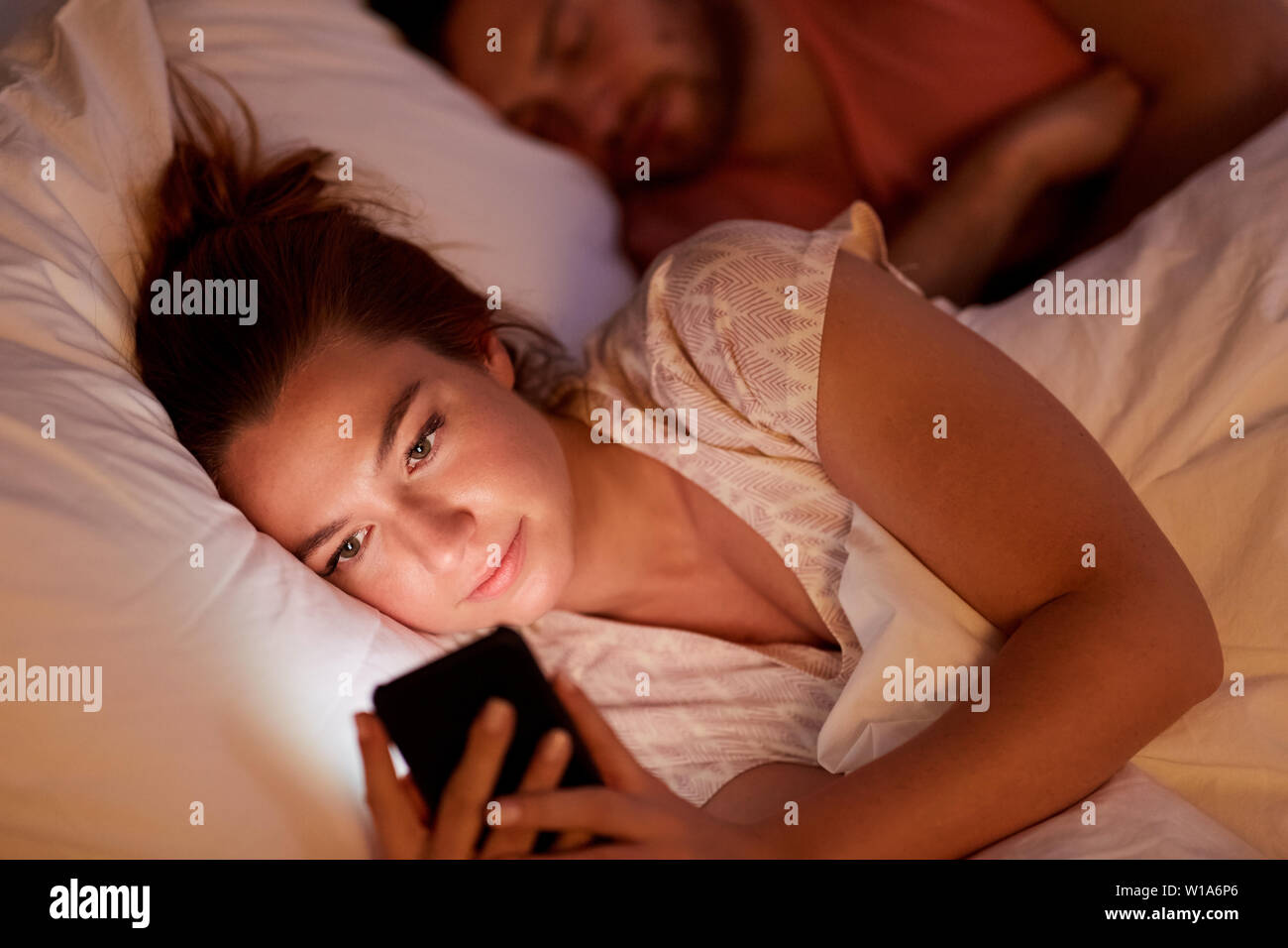 Woman using smartphone alors qu'ami est en train de dormir Banque D'Images