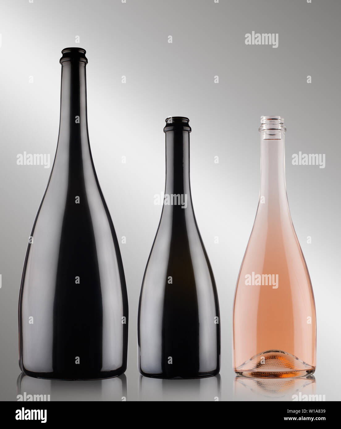 Vue de face de trois gros plan de différentes tailles des bouteilles de champagne vide avec aucune étiquette deux noire et une rose sur fond gris Banque D'Images