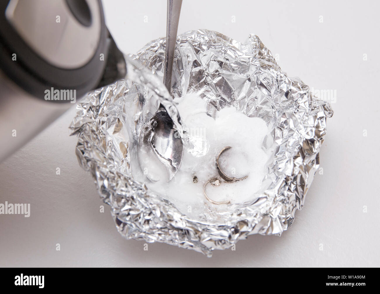 Une solution de bicarbonate de soude (bicarbonate de sodium) et de l'eau  chaude permettra d'liminer la ternissure de l'argent lorsque l'argent est  en contact avec un morceau de max euwe Photo Stock -