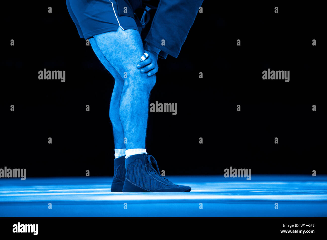 La lutte des hommes sur un tapis de lutte jaune dans la salle de sport. Filtre de couleur bleu. Banque D'Images