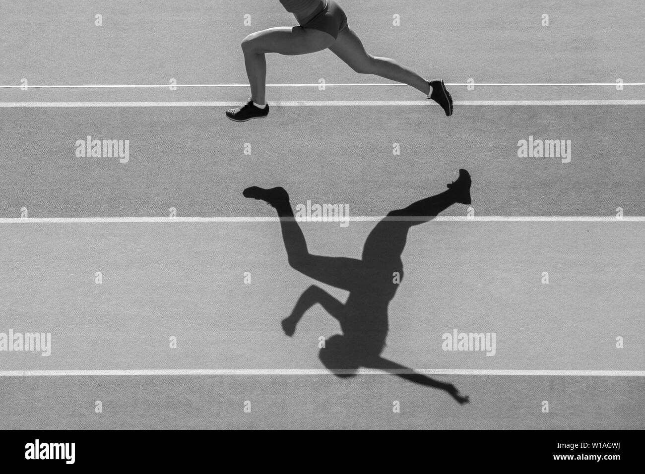 Un caucasian woman runner jogger running en silhouette sur l'arrière-plan du stade. Couleur Noir et blanc. Banque D'Images