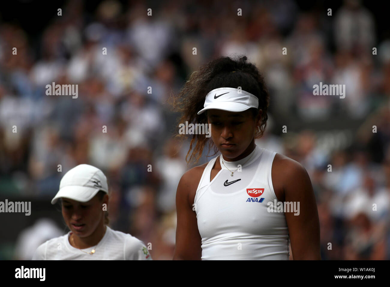 Wimbledon, Royaume-Uni. 1 juillet 2019 - numéro 2 du Japon Osaka Naomi semences se bloque sa tête au cours de son premier tour à perte de Yulia Putintseva Kazakhstan, à gauche, au cours de l'action du premier cycle sur le Court Central de Wimbledon. Crédit : Adam Stoltman/Alamy Live News Banque D'Images