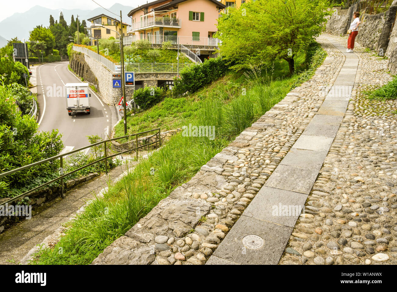 Le lac de Côme, Italie - Juin 2019 : sentier pédestre avec marqueur métallique sur le sol sur la route d'un sentier le long d'une partie du lac - la Voie verte del Lago Banque D'Images