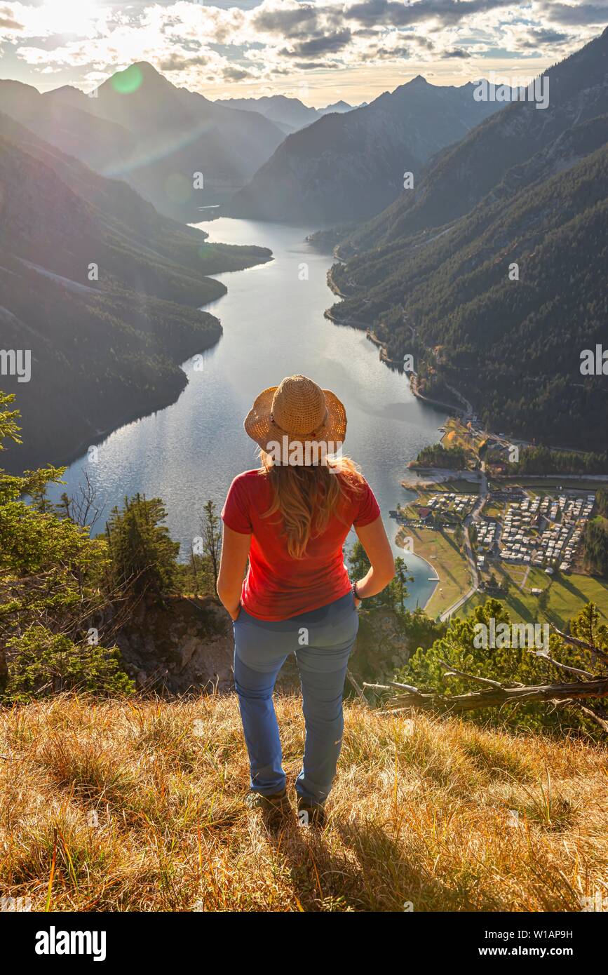 Female hiker avec un chapeau de soleil à dans la distance, le lac Plansee, Alpes Ammergau, district de Reutte, Tyrol, Autriche Banque D'Images