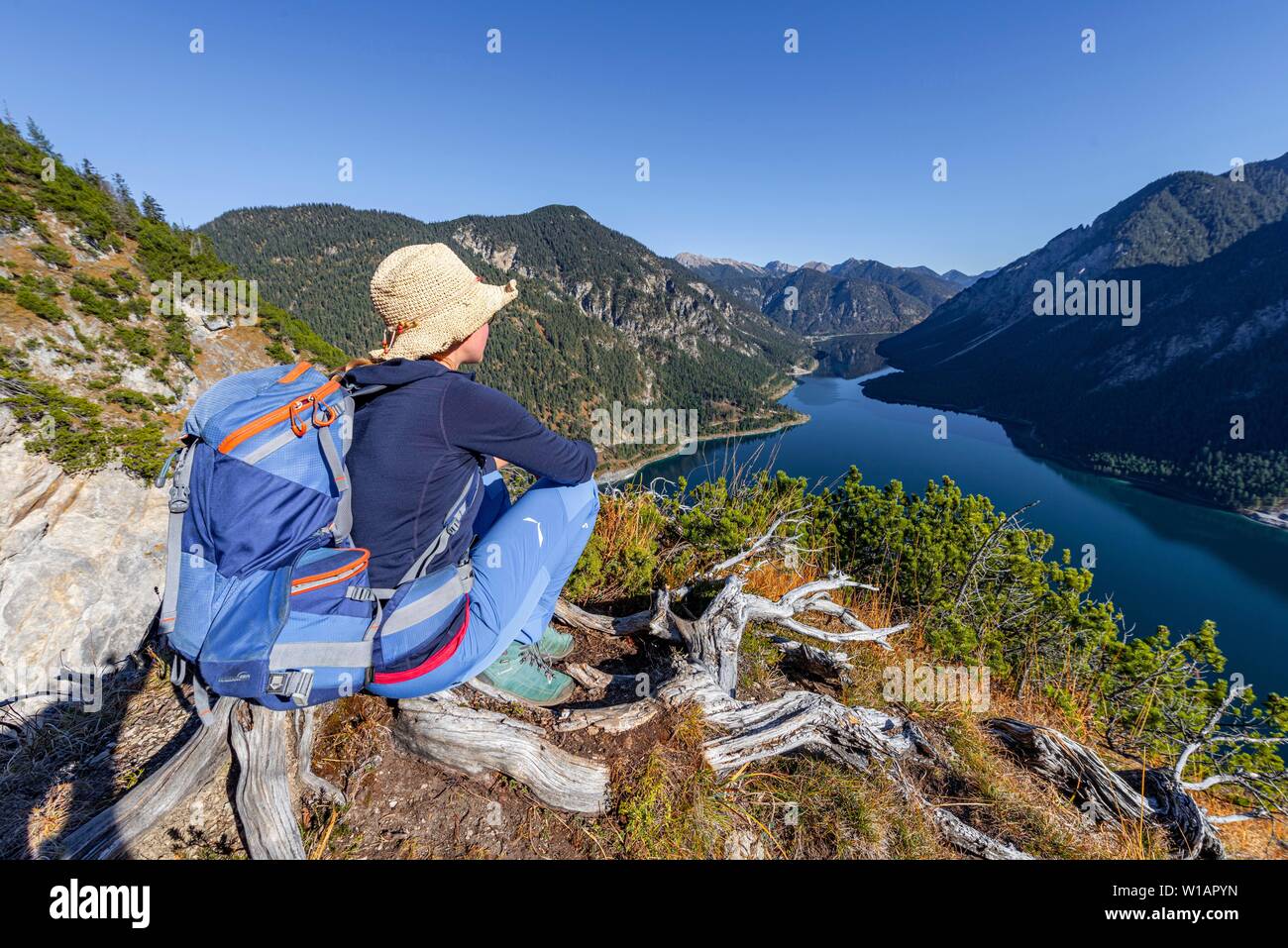 Female hiker resting et à la recherche dans la distance, Schonjochl à l'arrière, le lac Plansee, Alpes Ammergau, district de Reutte, Tyrol, Autriche Banque D'Images