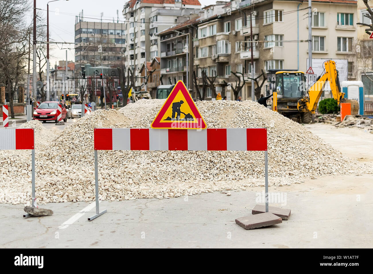 Le signe de chantiers sur rouge blanc barrière devant un tas de gravier sur une rue de la ville. Construction et réparation des routes en asphalte dans une ville. Ville im Banque D'Images