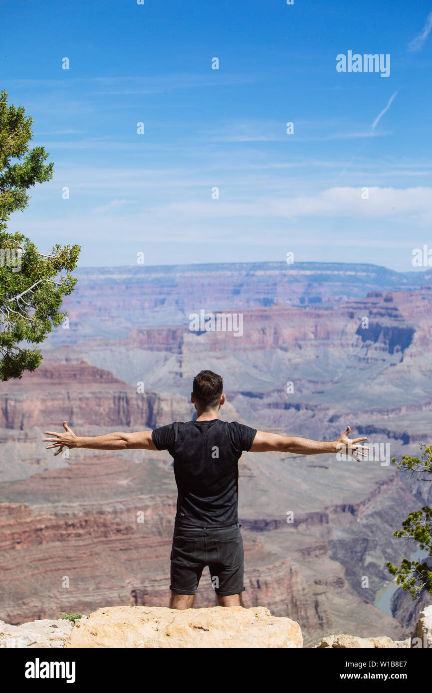 L'homme tourisme avec bras ouverts vers le canyon à proximité d'une falaise, à South Rim du Grand Canyon National Park, Arizona, USA Banque D'Images
