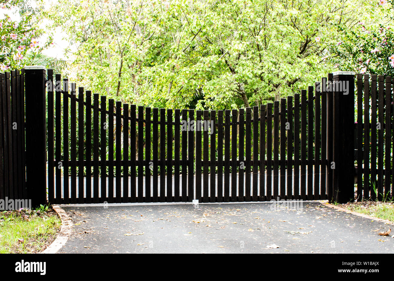 L'entrée en bois Portes d'entrée de la propriété situé dans le jardin avec clôture bois d'arbustes et arbres en arrière-plan Banque D'Images