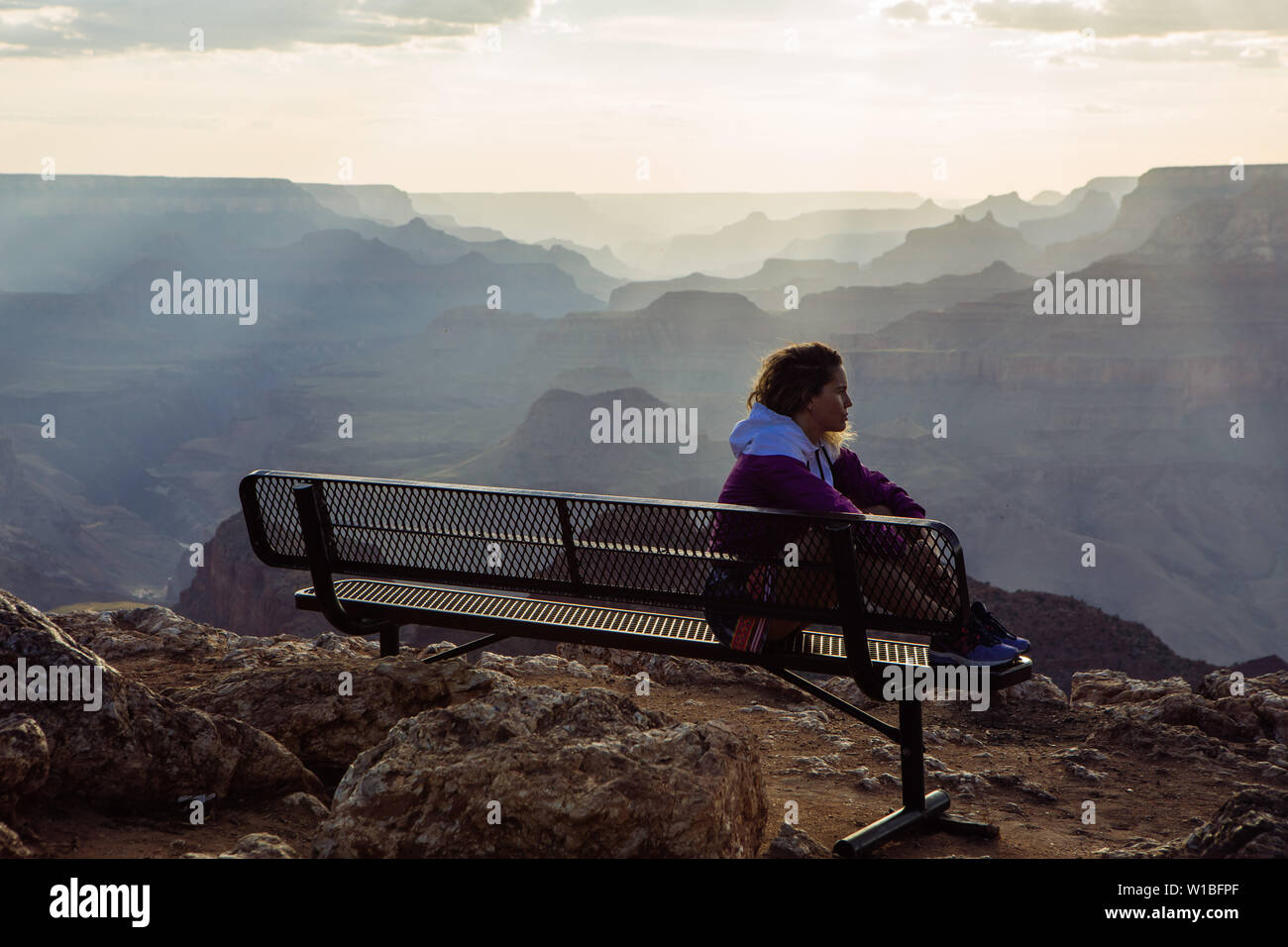 De race blanche, aux cheveux bouclés profil femme touristiques regardant le coucher du soleil à partir d'un banc à Desert View, le Parc National du Grand Canyon, Arizona, USA Banque D'Images
