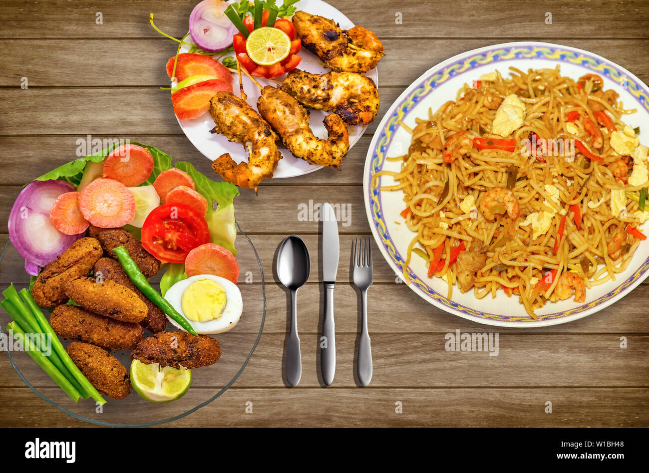 Indiens les repas de poulet épicé nouilles croustillantes chowmein avec les bâtonnets de poisson et crevettes frits servis avec salade. Banque D'Images