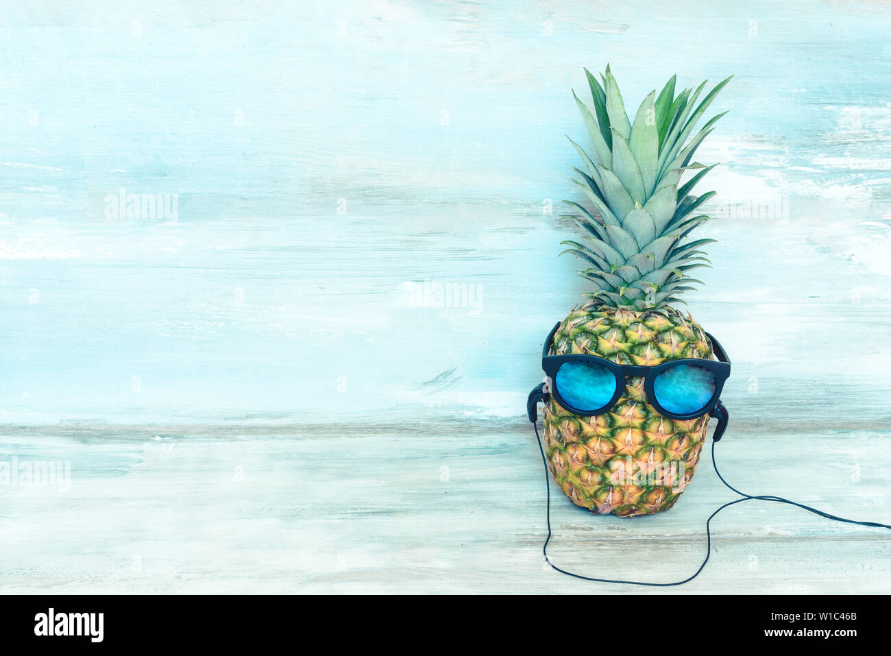 Ananas mûrs avec lunettes miroir bleu et le casque en face d'une rustique en bois bleu arrière-plan. Banque D'Images