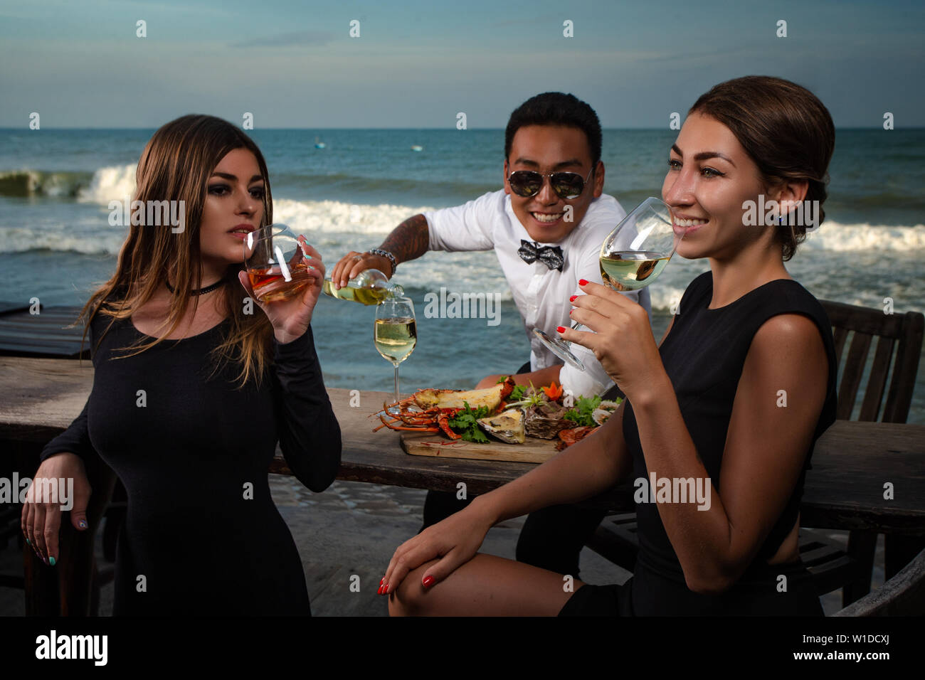 Amis dans un restaurant de fruits de mer - cheers avec verres à vin Banque D'Images