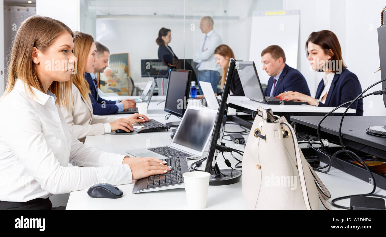 Agréable jeune femme positive joyeux concentrés sur travailler avec ordinateur portable en espace de coworking Banque D'Images