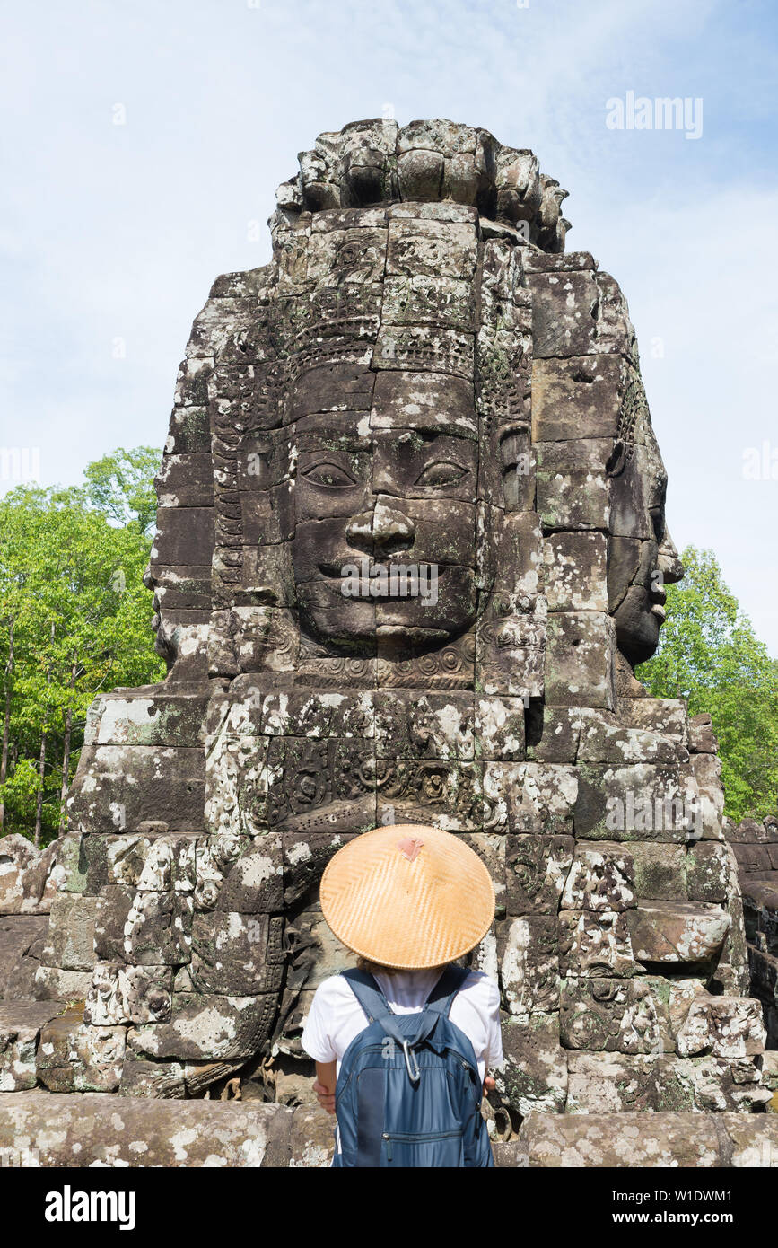 Femme au temple Bayon à la pierre à visages, Angkor Thom, lumière du matin, ciel bleu clair. Concept la méditation, célèbre destination de voyage, Banque D'Images