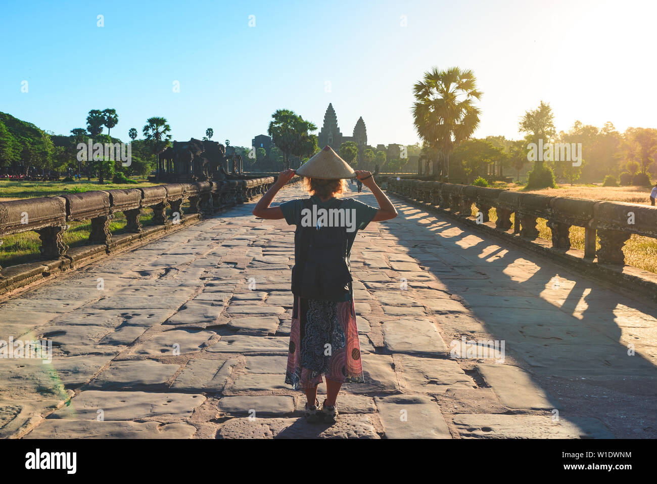Femme au temple Bayon à la pierre à visages, Angkor Thom, lumière du matin, ciel bleu clair. Concept la méditation, célèbre destination de voyage, Banque D'Images