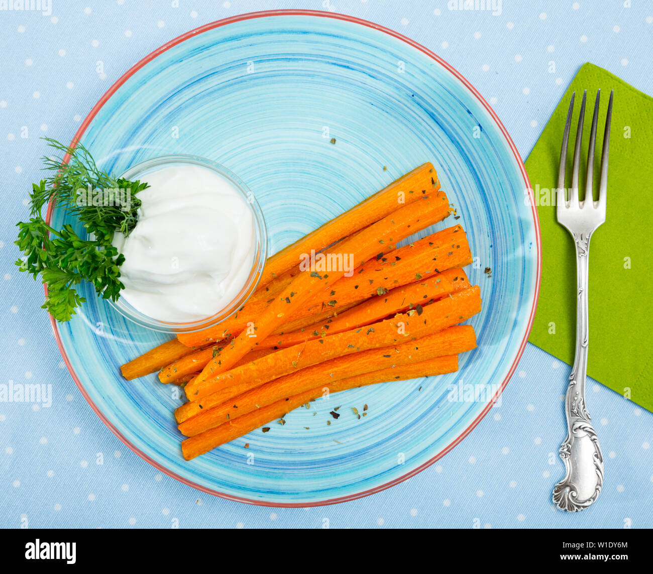 Vue de dessus du vitrage bâtonnets de carottes à la vapeur servi avec la crème fraîche et les verts Banque D'Images