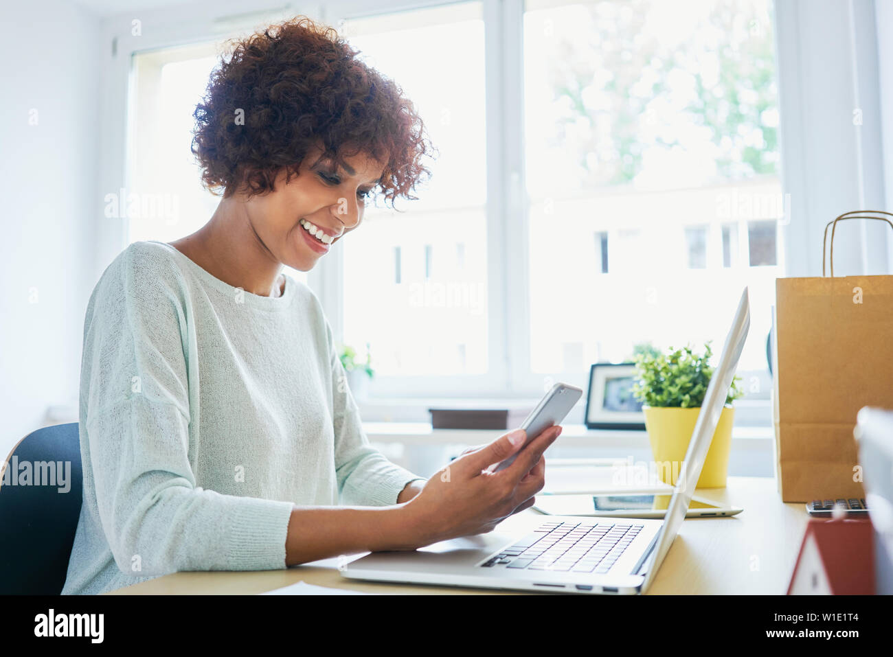 Femme à l'aide de son portable, bureau de travail à domicile Banque D'Images