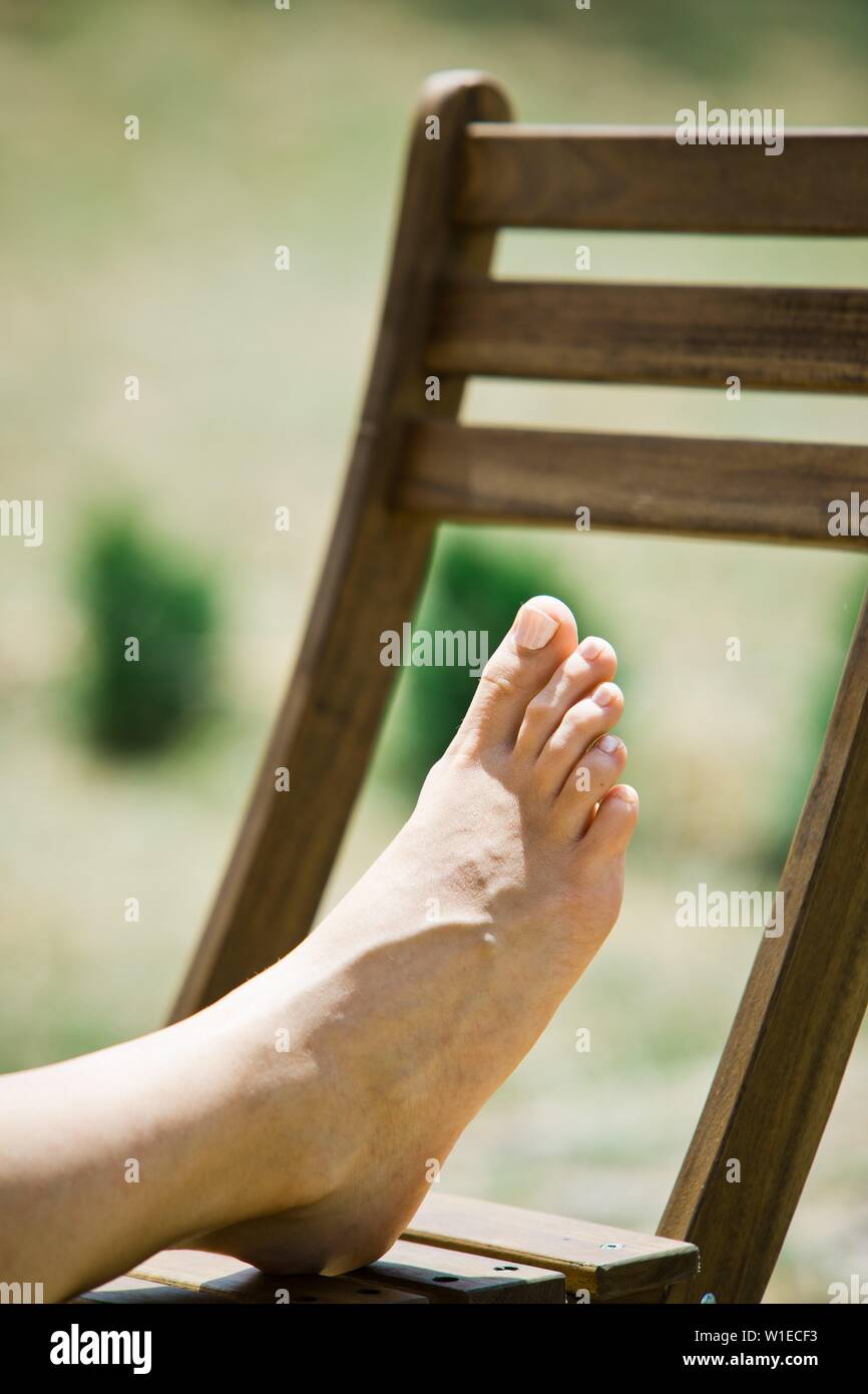 Woman's foot sur une chaise en bois, bains de soleil Banque D'Images
