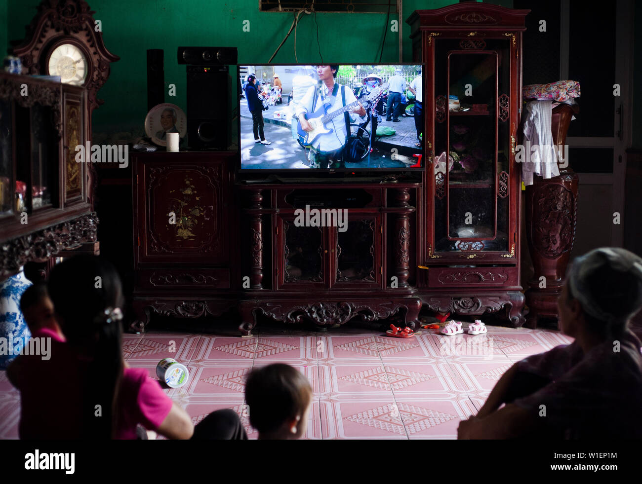 Famille vietnamienne à regarder la télévision dans leur chambre dans le Delta du Fleuve Rouge, au Vietnam Banque D'Images