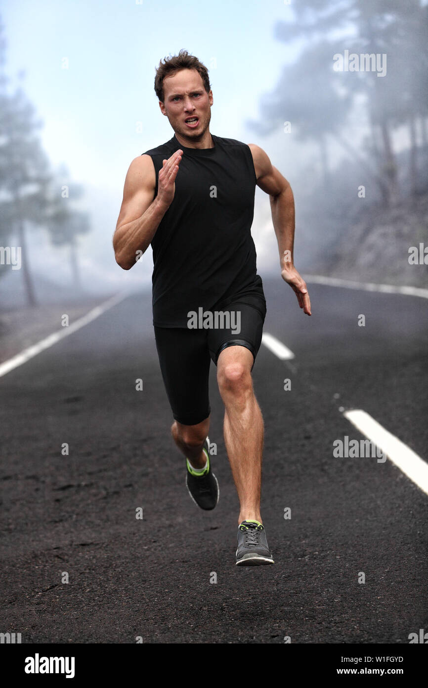 L'exécution d'entraînement sprint homme coureur sur route de montagne. Le jogging homme modèle de remise en forme hors de la formation pour le marathon sur route forestière en nature paysage incroyable. Banque D'Images