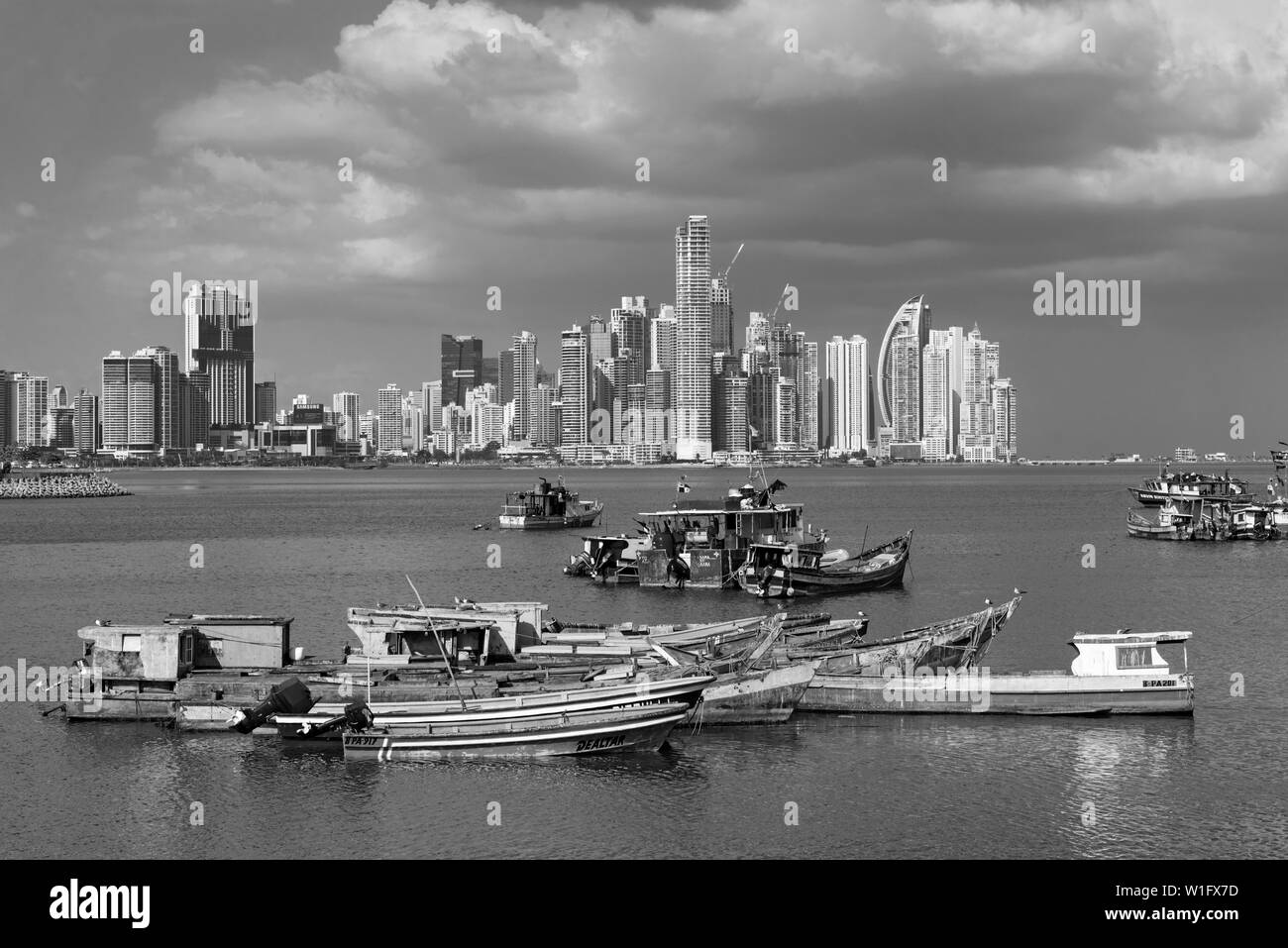 Vieux bateaux de pêche en bois en face de la skyline de la ville de Panama, Panama en noir et blanc Banque D'Images
