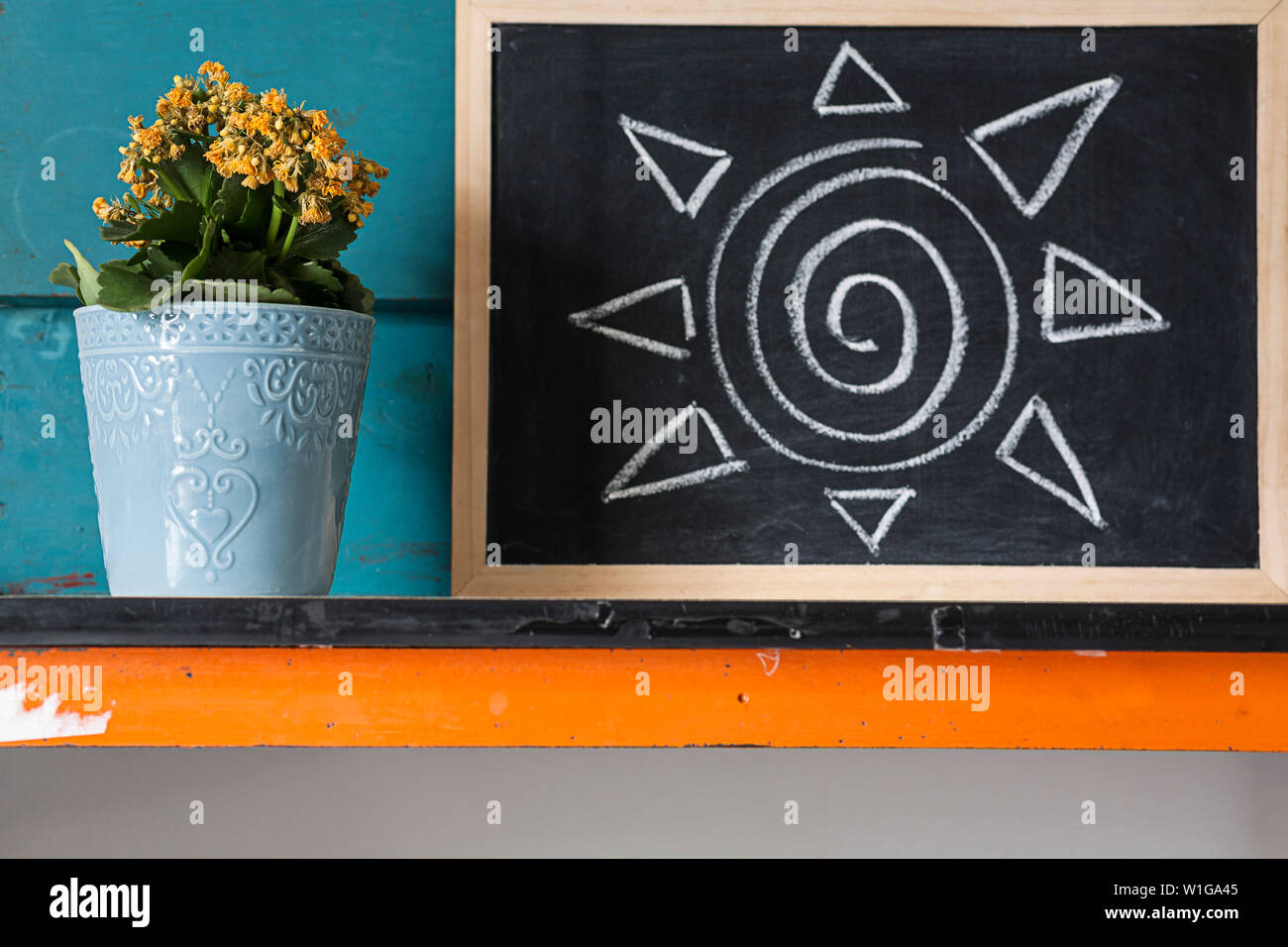 Image créative de fleurs jaunes en pot avec fond bleu avec l'illustre des conseils sur des plantes à la craie sur un tableau noir. Banque D'Images