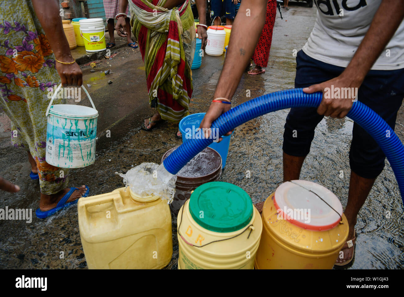 Un résident local remplit les contenants avec de l'eau potable à partir d'un navire-citerne municipal à Kolkata.L'Inde est confrontée à la pire crise de l'eau de son histoire, et 21 villes indiennes vont manquer d'eau d'ici 2020. Banque D'Images