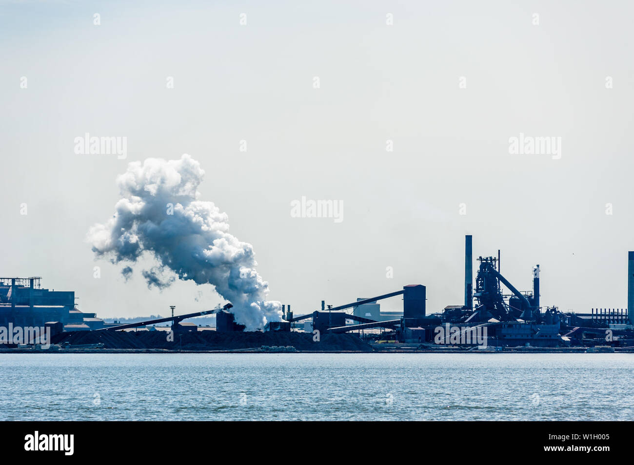 HAMILTON, CANADA - 21 avril 2018 : un grand panache de vapeur est à la dérive est libéré à une usine d'acier sur la rive du port de Hamilton. Banque D'Images