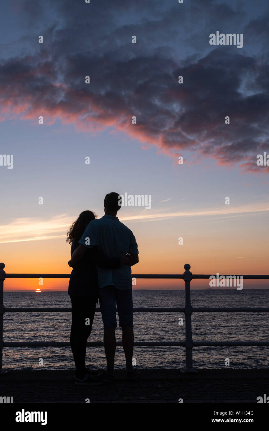 Pays de Galles Aberystwyth UK, mardi 02 juillet 2019 Météo Royaume-uni : un couple embrasser, silhouetté contre le ciel tout en regardant le coucher du soleil glorieux à Aberystwyth, sur la côte de la Baie de Cardigan, l'ouest du pays de Galles. Crédit photo : Keith Morris//Alamy Live News Banque D'Images