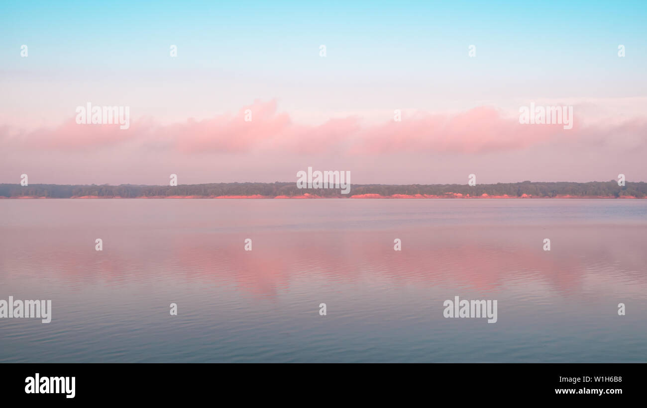 Reflet de nuages rose sur un lac. Que Saylorville Lake, près de Polk City, Iowa, États-Unis. Heure Bleue, barbe les nuages, le lever du soleil dans le Midwest. Banque D'Images