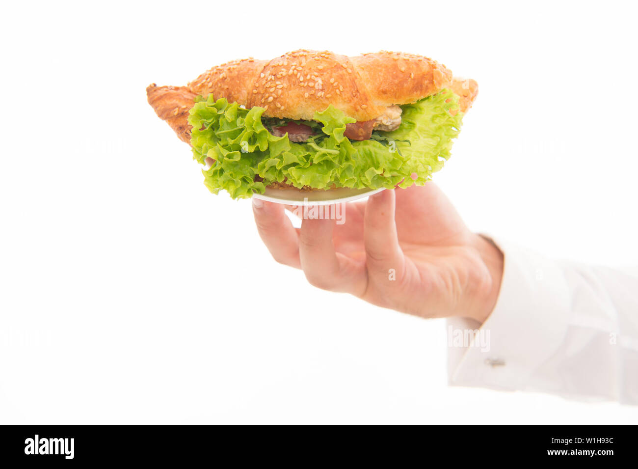 Les Calories et les régimes amaigrissants. Servant un croissant farci de laitues et légumes frais. Cafe concept. Alimentation saine. Croissant traditionnel français. Main de garçon porter la plaque avec le plat. De délicieux croissants. Banque D'Images
