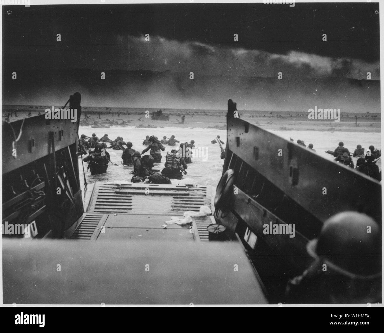 Photographie de l'invasion de Normandie ; Portée et contenu : la légende originale : en bas de la rampe d'un chaland de débarquement de la Garde côtière canadienne les soldats Yankee storm vers la plage de balayage-fire de défenseurs des nazis dans l'invasion du Jour J de la côte française. L'avance des troupes peut être vu à plat sous la mitrailleuse mortelle de la résistance des Allemands. Bientôt, les Nazis ont été repoussés en vertu de la grande invasion jeté à la Garde côtière et la marine de plaisance amphibie. Notes générales : c'est le titre officiel attribué par la Garde côtière. Banque D'Images