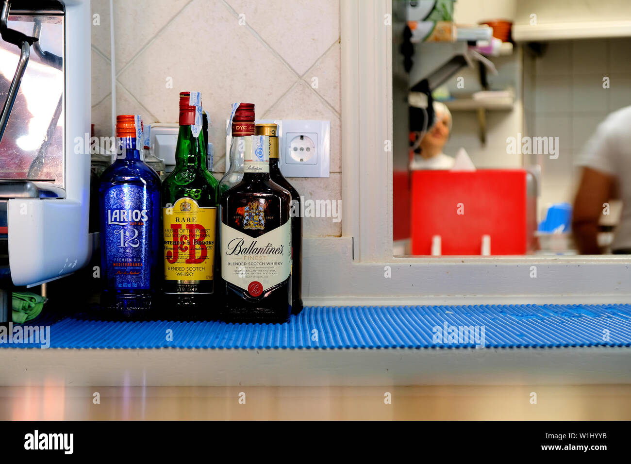 Bouteilles de gin et whisky blended Scotch derrière le comptoir dans un restaurant à Grenade, en Espagne, près de la fenêtre de la cuisine du restaurant. Banque D'Images