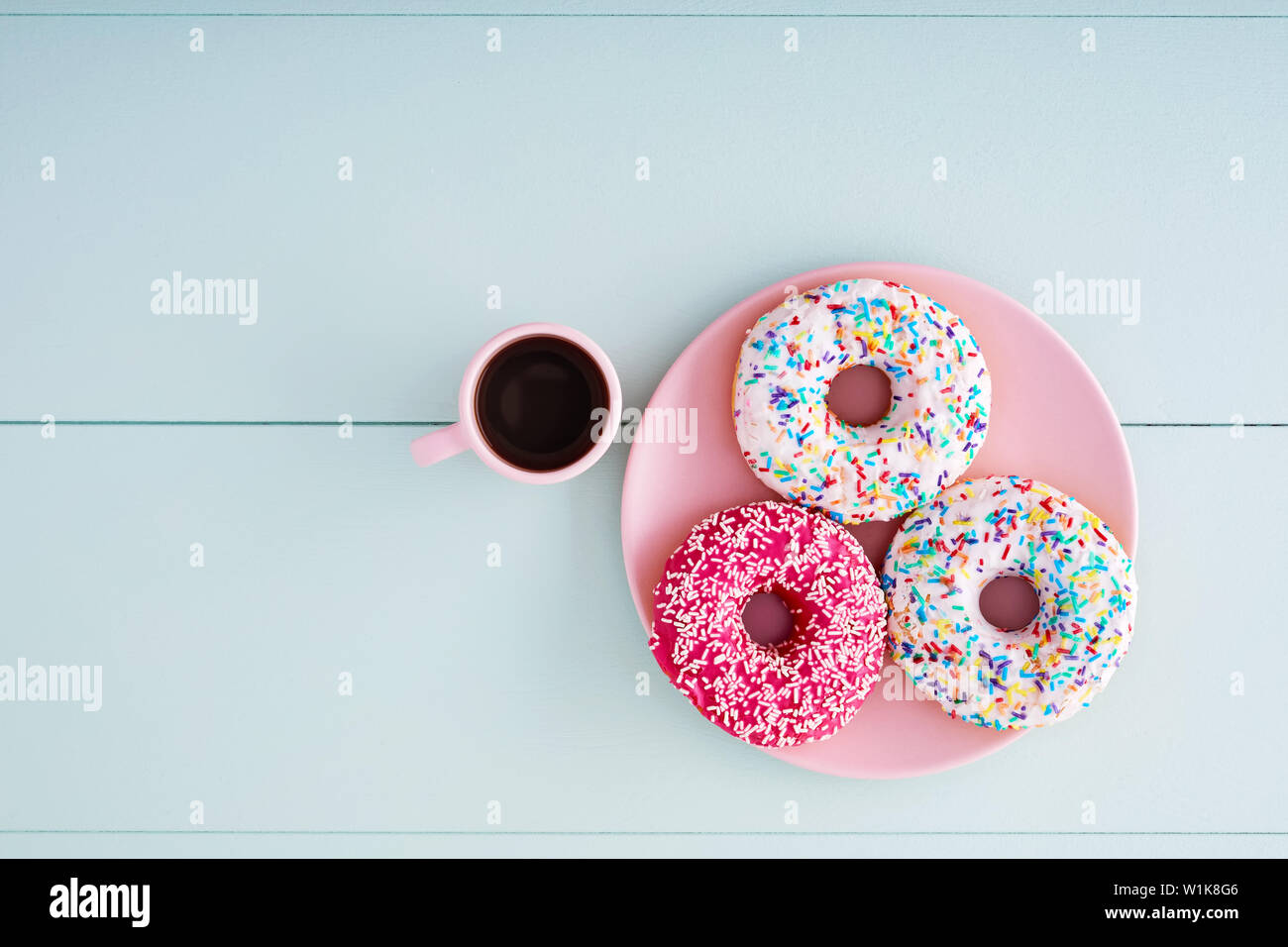 Donuts colorés dans une plaque rose rose avec du cappuccino tasse sur une  table en bois bleu pastel background with copy space. Vue de dessus Photo  Stock - Alamy