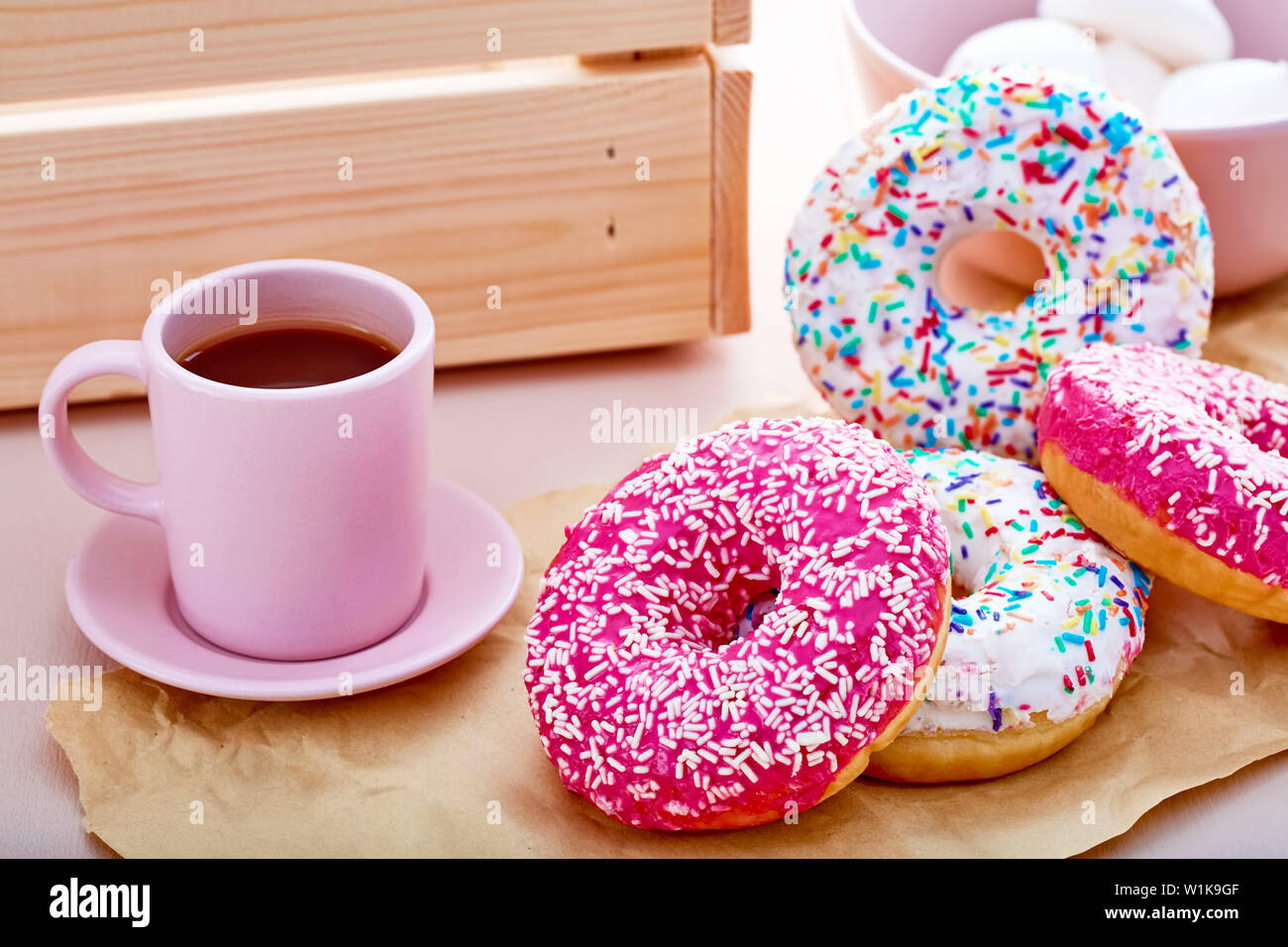Donuts colorés sur papier rose avec tasse de café, les guimauves et une  caisse sur table. Vue en gros plan Photo Stock - Alamy