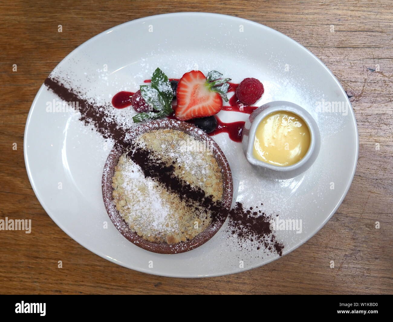 Londres, Royaume-Uni - Juin 2019 - Crumble aux pommes et crème anglaise pour le dessert à l'Applebee's Fish au Borough Market Banque D'Images