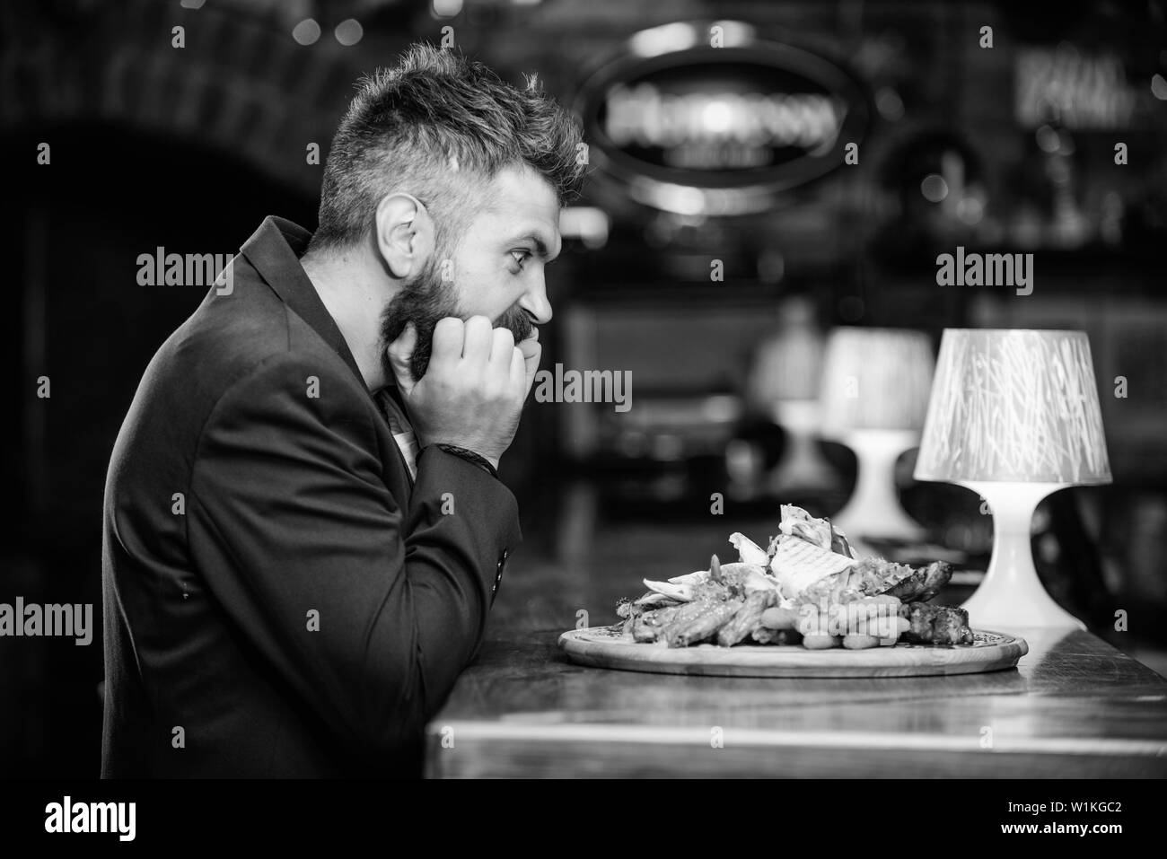 Profitez de repas. Des calories. Tricher repas. Hipster faim manger pub aliments frits. Costume officiel Gestionnaire de siéger au comptoir du bar. Délicieux repas. L'homme a reçu de pommes de terre frites repas avec les bâtonnets de poisson viande. Banque D'Images