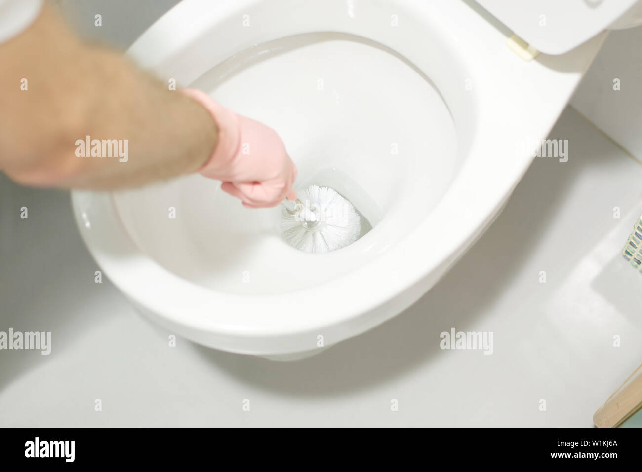 Mari avec une brosse wc nettoyer la salle de bain siège faisant quelques travaux ménagers. Banque D'Images