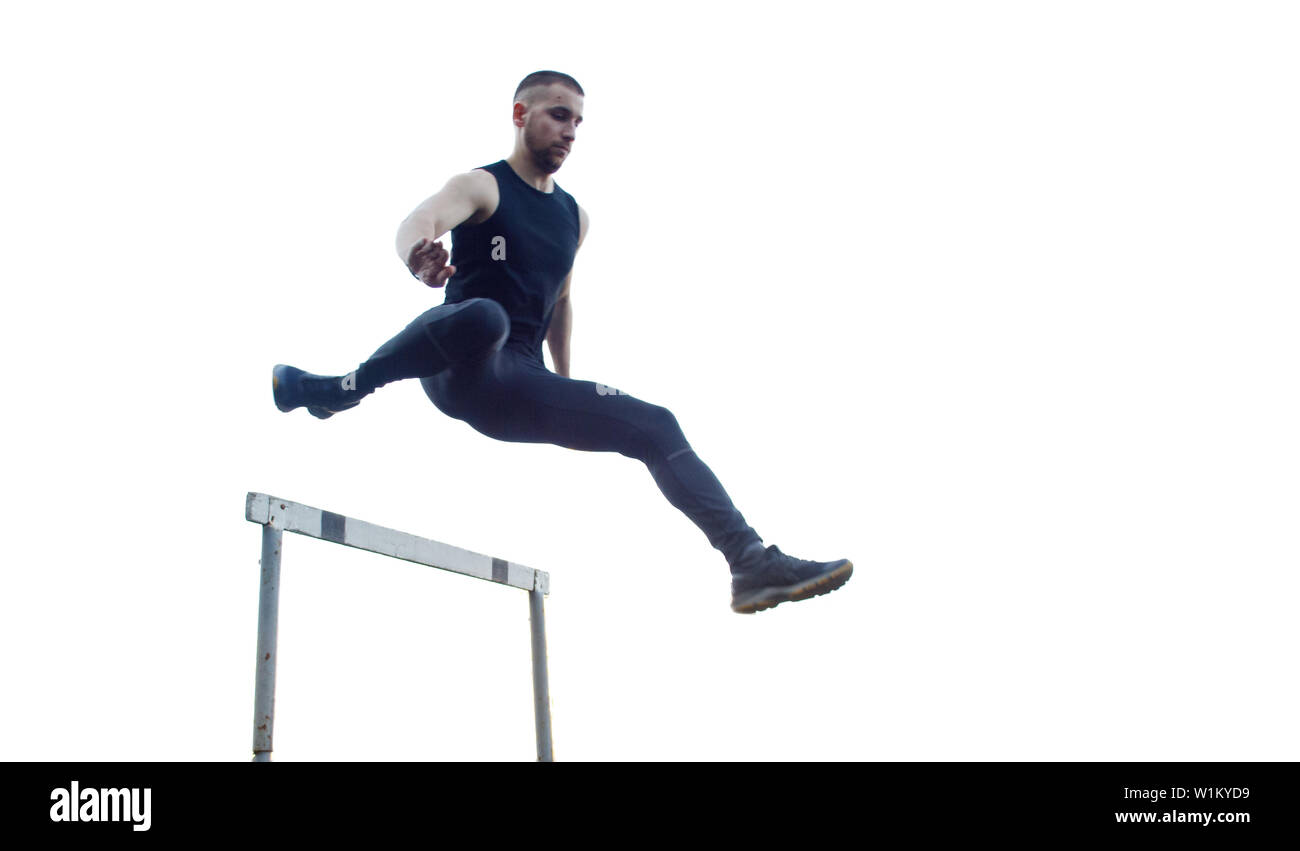 Un homme de race blanche dans un saut sur un obstacle. d'exécution sur le stade. Track and field runner dans le sport en uniforme. vol énergique des activités physiques. Banque D'Images