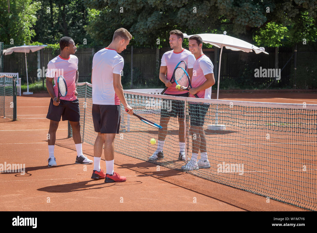 Groupe de jeunes hommes jouant au tennis sur une journée ensoleillée, Bavière, Allemagne Banque D'Images