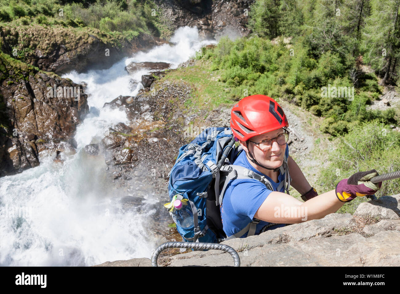 Woman climbing rock face via ferrata vers Cascade Stuibenfall, Otztal, Tyrol, Autriche Banque D'Images