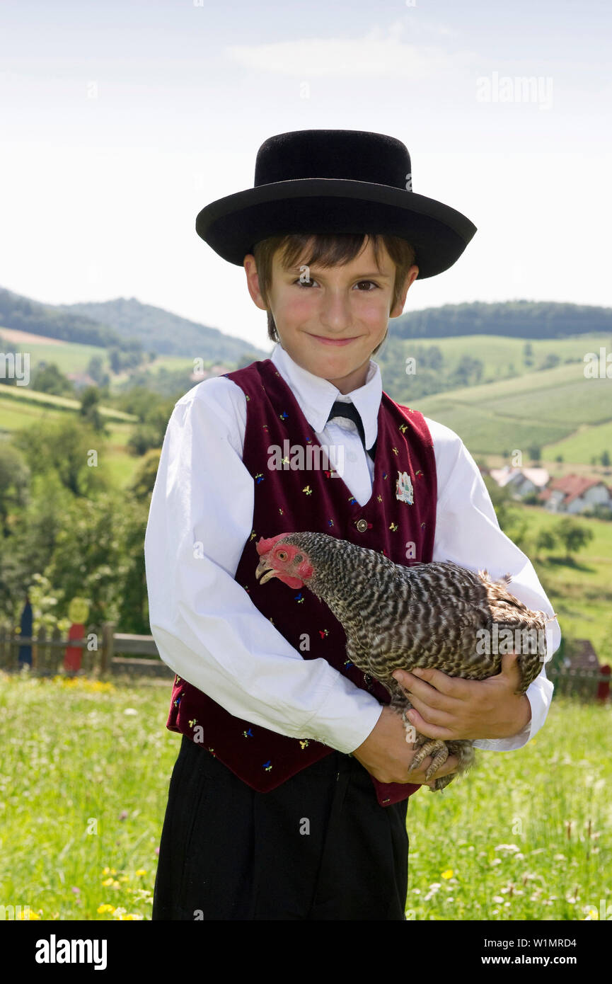 Boy holding a chicken portant des vêtements traditionnel de la Forêt Noire, Gottertal, Baden-Wurttemberg, Allemagne Banque D'Images