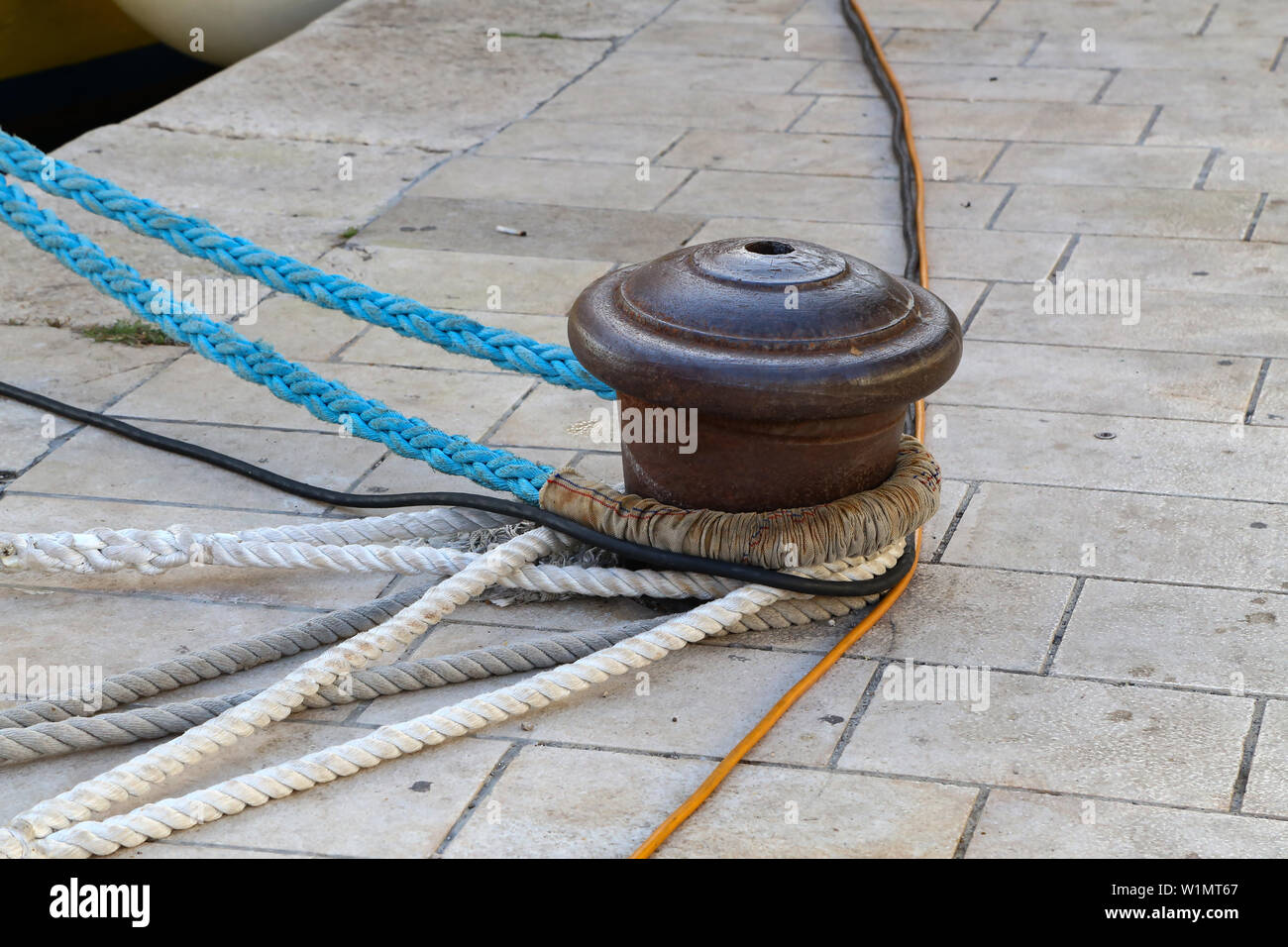 Bollard avec un cordage enroulé autour de lui. Bateaux amarrés au port de plaisance. Banque D'Images
