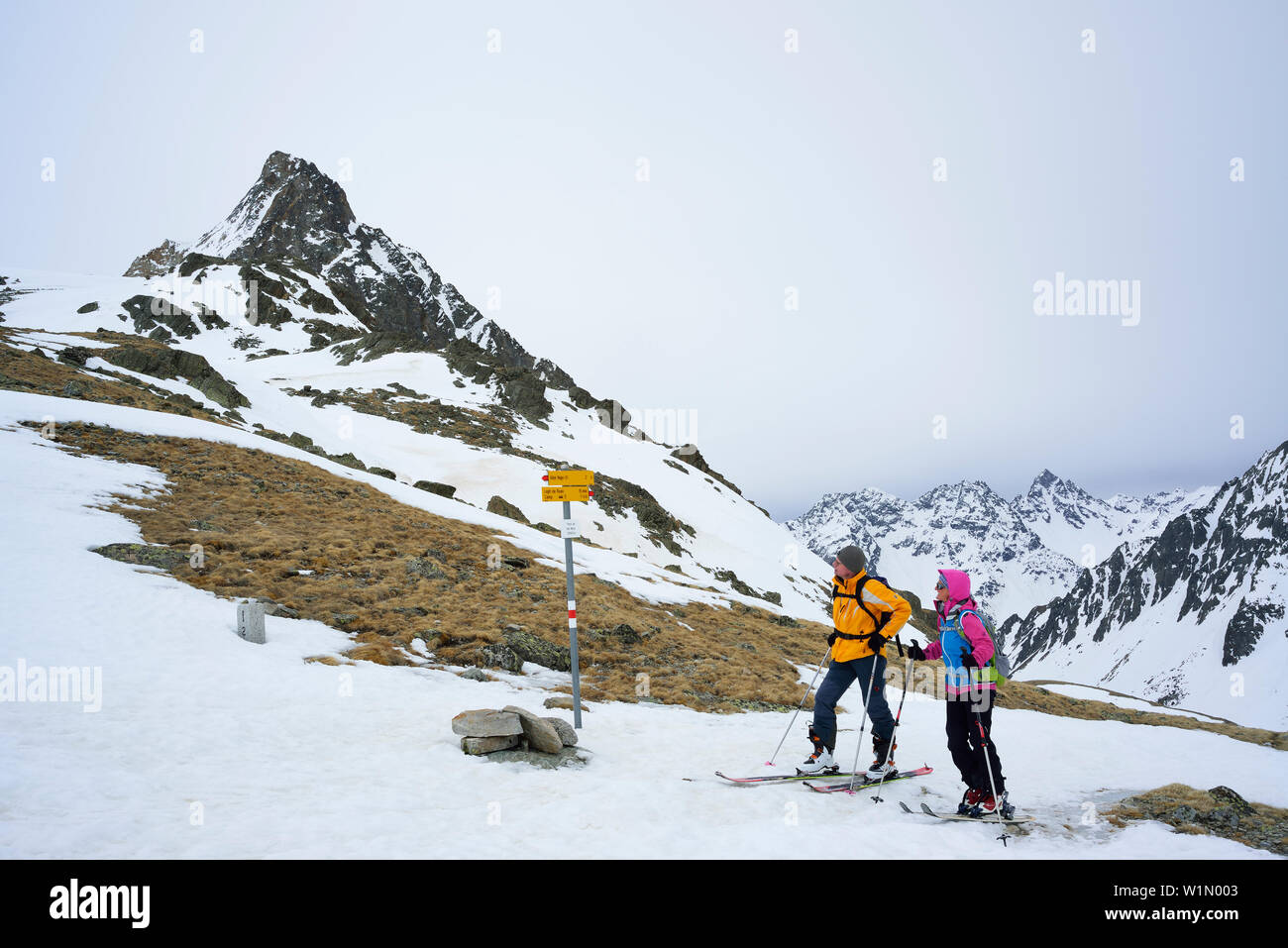 Deux skieurs de l'arrière-pays de la lecture d'un panneau routier, le maïs da Camp en arrière-plan, le Piz Paradisin, Val Poschiavo, Engadine, Canton des Grisons, Suisse Banque D'Images