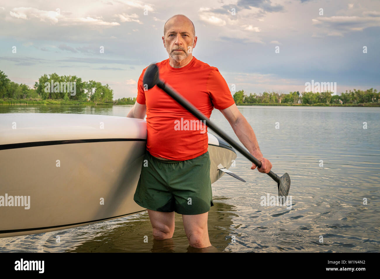 Portrait de l'environnement d'un pagayeur senior avec son stand up paddleboard sur un lac dans le Colorado. Banque D'Images