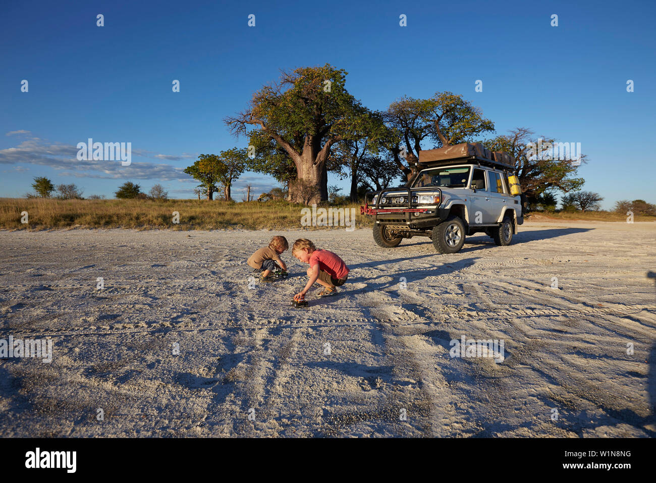 Garçons jouant dans le sable au coucher du soleil, Tutume, Nxai Pan National Park, Botswana Banque D'Images