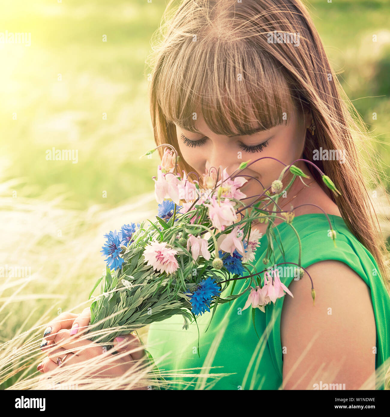 Jeune fille sensuelle sentir un bouquet de fleurs sauvages Banque D'Images