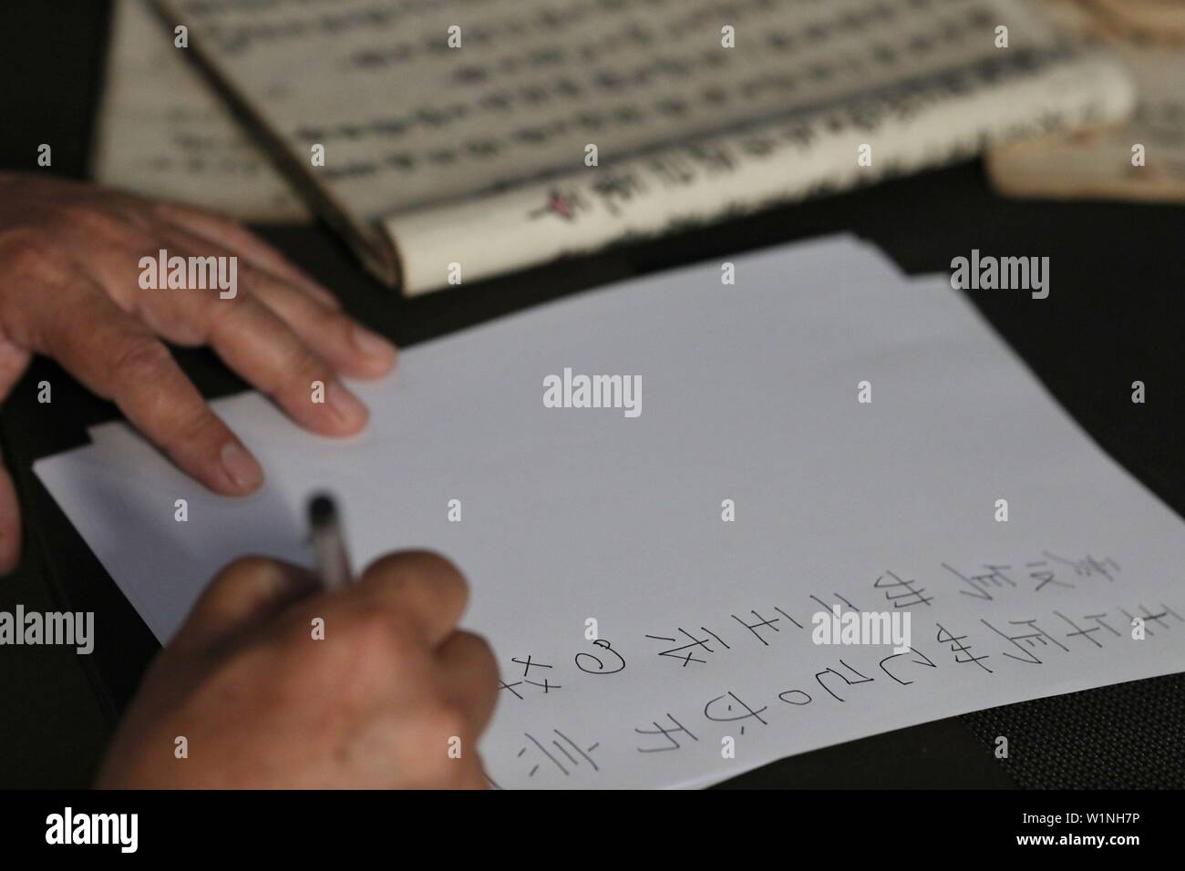 (190703) -- SANDU, le 3 juillet 2019 (Xinhua) -- chercheur culturel rend Shizhao Wei copies manuscrites d'un texte en script Shui dans le comté de Sandu, le sud-ouest de la Chine dans la province du Guizhou, le 3 juillet 2019. Wei a commencé à apprendre Shui script dans son enfance. Jusqu'à présent, ses traductions en chinois moderne de textes dans Shui script ont s'élevait à près de trois millions de caractères. Le Shui script est le système d'écriture pictographique unique utilisé par le peuple Shui dans le sud-ouest de la Chine de tenir des registres de leur culture. Comme le bronze et l'os d'oracle les inscriptions de la Chine ancienne, le Shui script se compose de logogrammes inve Banque D'Images
