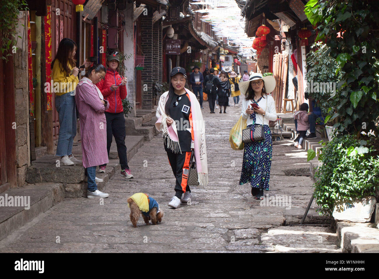 La Chine, Lijang. Colorants fille sa mère poils sur la rue animée de l'ancienne ville de Lijiang, Yunnan province Banque D'Images