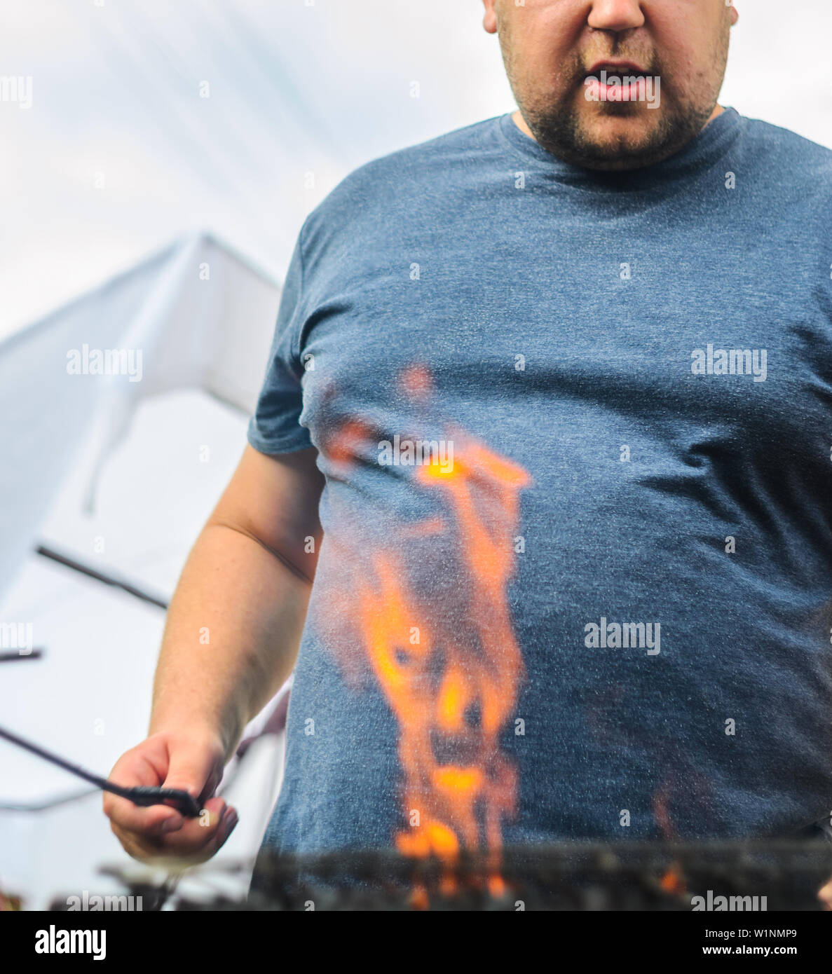 Fat Man est la cuisson sur le grill sur la rue. Haute flamme dégénérer sur  le grill. Arrière-plan de barbecue avec de l'espace vide Photo Stock - Alamy
